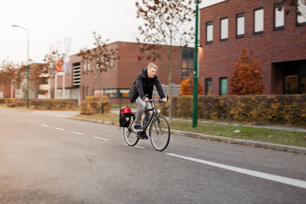 Afbeelding van de directuer van AMP Groep die door een woonwijk fietst terwijl hij onderweg naar het werk is.