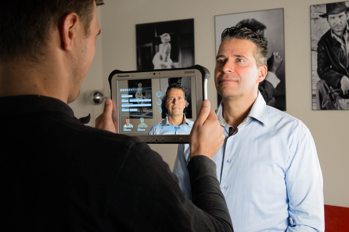 Afbeelding van een medewerker van AMP Groep die de echtheid van iemand zijn identiteit controleert via een speciale tablet.