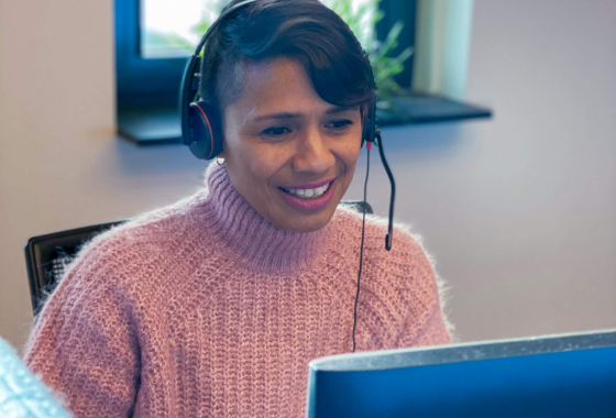 Afbeelding van een vrouwelijke AMP Groep medewerker met een headset die klanten op een vriendelijke wijze te woord staat.