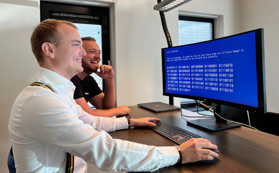 Afbeelding van twee medewerkers die achter een computerscherm zitten te werken aan nieuwe technologie binnen AMP Groep.