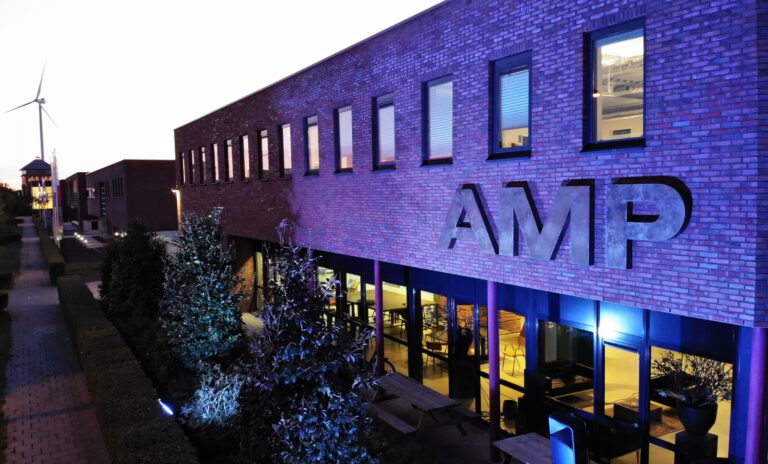 het kantoor van AMP, waar duidelijk het logo te zien is op een modern gebouw